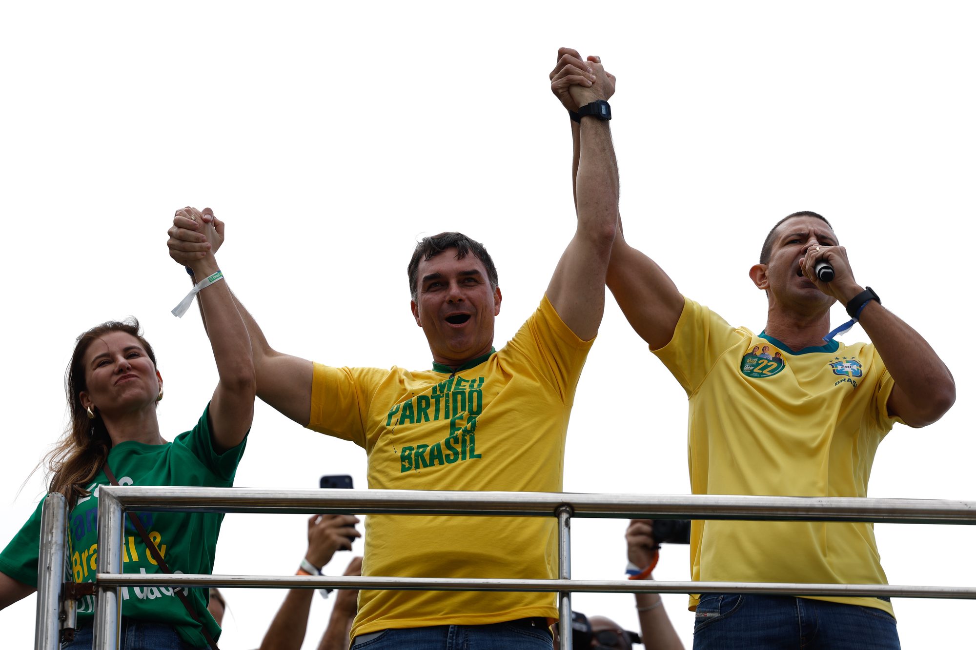 Flávio Bolsonaro ergue as mãos com aliados no lançamento da campanha, em comício na praia de Copacabana (RJ), em 16 de agosto de 2026
